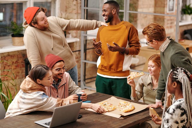 Group of people gathered around a table with pizza on it